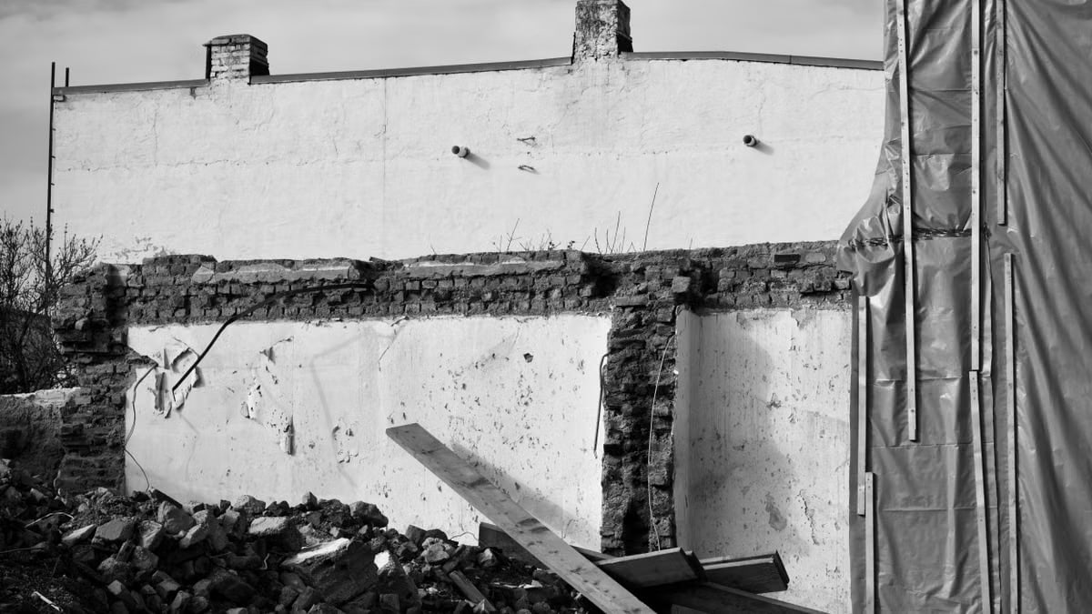Black and white photo of a demolished building showing exposed bricks and construction debris.